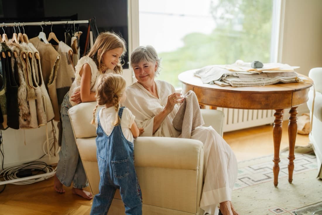 Birgitta Svensson hand-embroidering in her atelier, a rack of sheepskin pieces behind her
